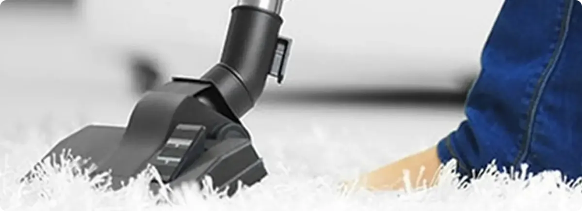 Close-up of a professional vacuuming a white carpet in Roca.